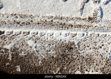 Close-up foto di una strada nella stagione invernale sulla neve sporca, un protettore è visibile dai pneumatici del carrello. Foto Stock