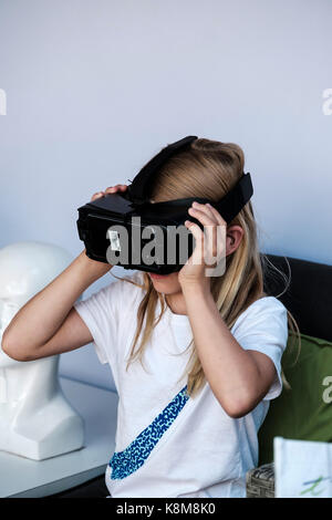 Giovane ragazza che indossa il visore VR Oculus Gear, l'apparecchiatura per realtà virtuale (VR) metaverse con il telefono Samsung. Foto Stock