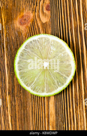 Fresh succosa fetta di verde lime, fotografato close-up su un vecchio tavolo di legno. Foto Stock