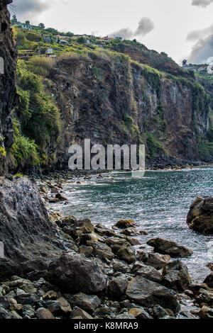 Cliff e rocce sull oceano atlantico in Isola di Madeira con case sulla parte superiore Foto Stock