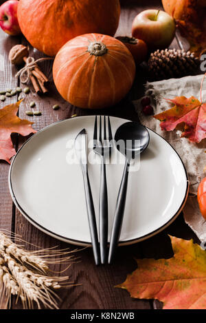 Cena di ringraziamento impostazione tabella con zucche, grano caduto foglie e nero posate. composizione verticale, il fuoco selettivo Foto Stock