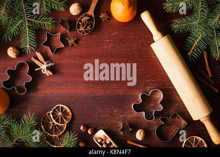 Vacanze invernali Vacanze di Natale anno nuovo sfondo con cookie cutters, spezie, dadi albero di natale e gingerbread cookie su sfondo di legno. vista superiore Foto Stock