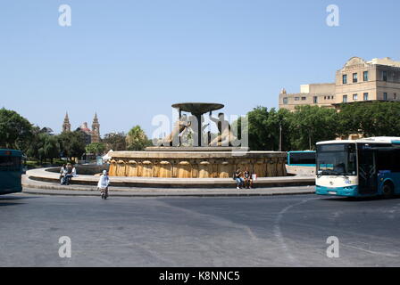 Autobus che arrivano presso la Fontana del Tritone, fuori La Valletta city gate, Malta Foto Stock