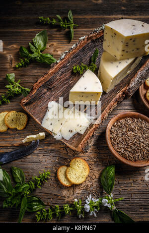 Concetto di formaggio su una corteccia di semi di cumino Foto Stock