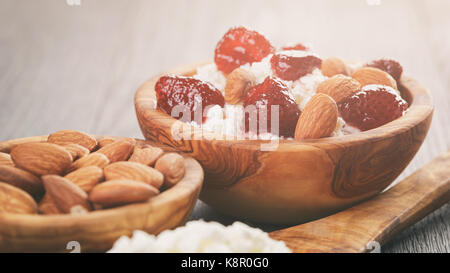 Formaggio con conserva di fragola in ciotola di legno su tavola in legno di quercia Foto Stock