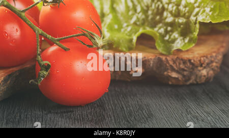 Romain fresca insalata verde e pomodori sulla scheda di oliva Foto Stock