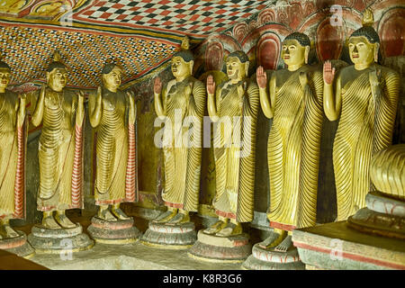 Una fila di statue di Buddha linea all'interno di una caverna nella grotta di dambulla comples vicino kandalarma in Sri Lanka. Foto Stock