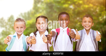 Ritratto di studenti mostrando pollice in alto segno contro gli alberi della foresta Foto Stock