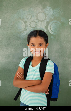 Digital immagine composita di ingranaggi bianchi su Blu Vernice spray contro il ritratto della scuola di Cute girl in piedi con le braccia incrociate Foto Stock