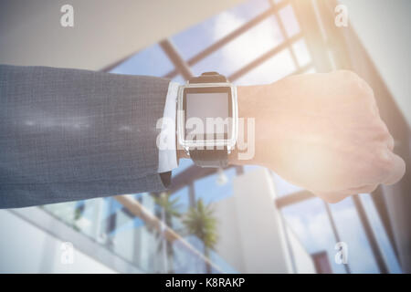 Ritagliate la mano di imprenditore indossando smart orologio contro basso angolo vista del soffitto di vetro in office Foto Stock