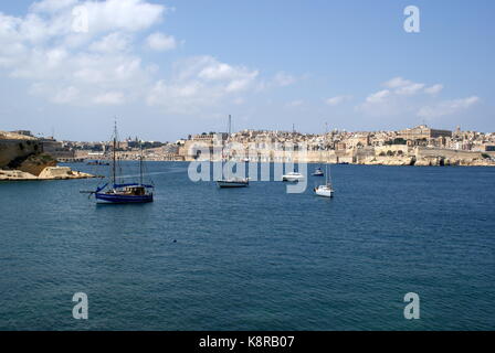 Barche a vela all'ancora nella baia di Rinella, Grand Harbour, di fronte alla città fortificata di Valletta, Malta Foto Stock