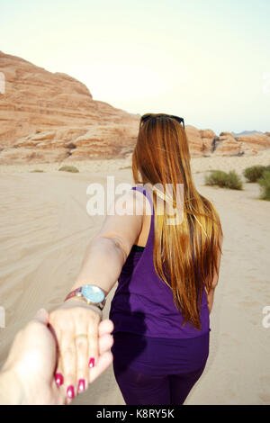 Un giovane camminando mano nella mano verso il deserto di wadi rum per esplorare esso Foto Stock