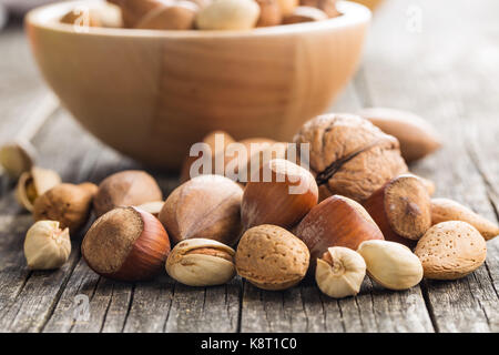 Diversi tipi di dadi in breve. Nocciole, noci, mandorle, noci pecan e i pistacchi sul vecchio tavolo in legno. Foto Stock