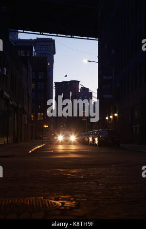 Lens Flare fari auto sotto il Manhattan e il Ponte di Brooklyn a notte in DUMBO. Foto Stock