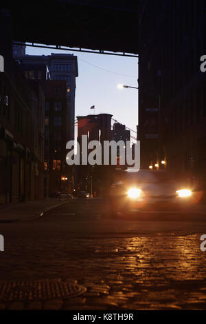 Lens Flare fari auto sotto il Manhattan e il Ponte di Brooklyn a notte in DUMBO. Foto Stock