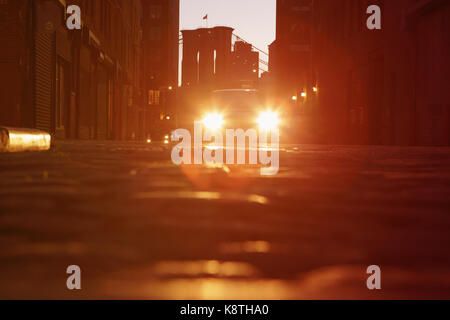 Lens Flare fari auto sotto il Manhattan e il Ponte di Brooklyn a notte in DUMBO. Foto Stock