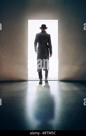 Silhouette uomo a piedi alla luce di apertura della porta in camera oscura. concetto di fuga Foto Stock