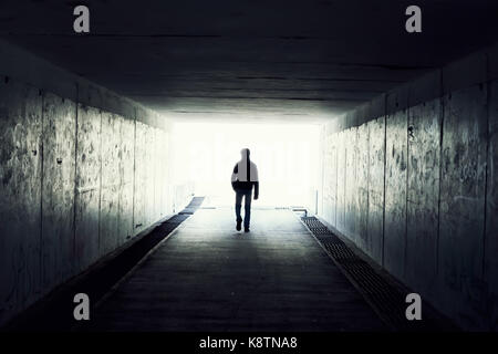 Silhouette in un tunnel della metropolitana. La luce alla fine del tunnel Foto Stock