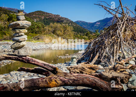 Un cairn e una capanna di driftwood sulla costa occidentale della Corsica Foto Stock