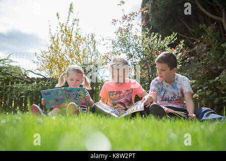 Lettura per bambini in giardino Foto Stock