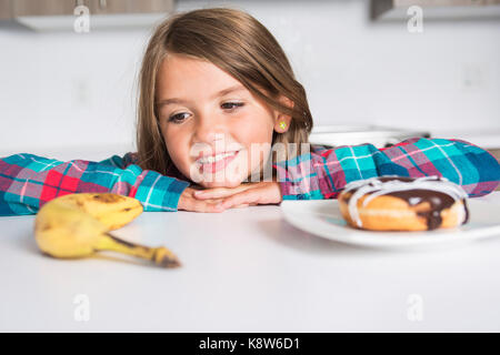 Kid scegliendo tra ortaggi sani e gustosi dolci Foto Stock