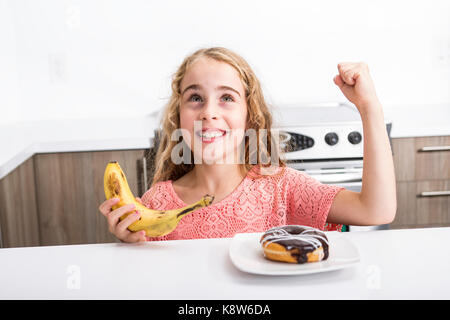 Kid scegliendo tra ortaggi sani e gustosi dolci Foto Stock