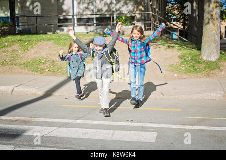 La scuola dei bambini attraversare la strada Foto Stock