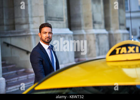 Un bel giovane imprenditore salire in un taxi Foto Stock