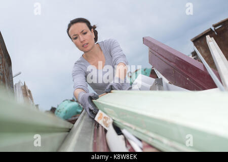 Mettere la spazzatura in skip Foto Stock