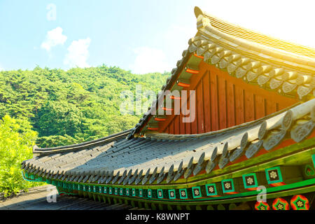 Sun flare visto sopra l'elemento del tetto di un monastero buddista situato vicino a Seoul - Corea del Sud Foto Stock