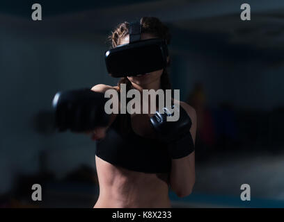 Giovani fighter boxer montare la ragazza di occhiali vr indossando guanti da boxe in formazione. gioco di boxe in realtà virtuale di 360 gradi. gioco futuristico Foto Stock