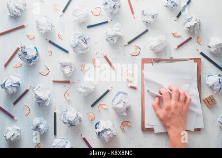 Carta sgualcita sfere con matite, tavoletta di legno, trucioli di matita e pagine bianche su un bianco sullo sfondo di legno. scrittura creativa concetto minimalista. f Foto Stock