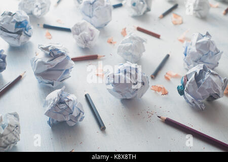 Close-up di carta sgualcita palle su un bianco sullo sfondo di legno con matite e trucioli di matita. scrittura creativa il concetto chiave di alta ancora in vita. Foto Stock