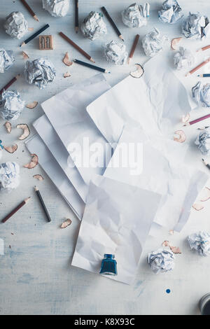 Carta bianca su un sfondo di legno con inkwell e diffusa la carta stropicciata sfere, matite e trucioli di matita. scrittura creativa concept Foto Stock
