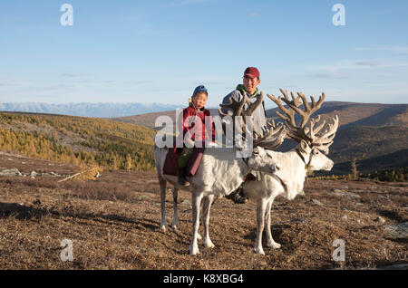 Tsaatan uomo, vestito di un tradizionale deel, viaggiando con le sue renne in un taiga del nord della Mongolia Foto Stock