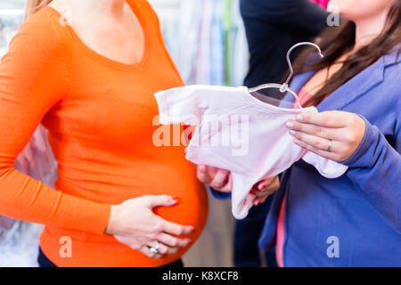 Aspettandosi la madre e signora di vendite in negozio baby Foto Stock