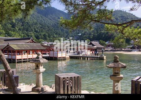 Il santuario di Itsukushima sull'isola di Miyajima in Giappone con il mare di fronte e le colline in background. Foto Stock