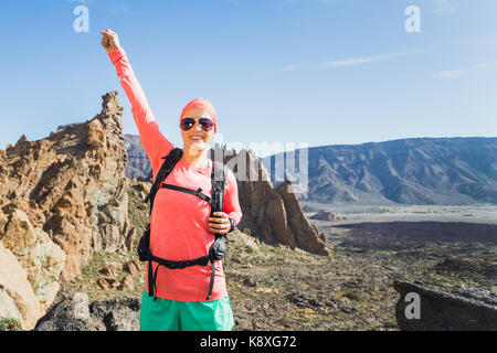 Escursioni o scalate successo con le braccia sollevate concetto. Guida femmina o escursionista celebrare sulla cima della montagna nel paesaggio di ispirazione sul sentiero roccioso piede Foto Stock