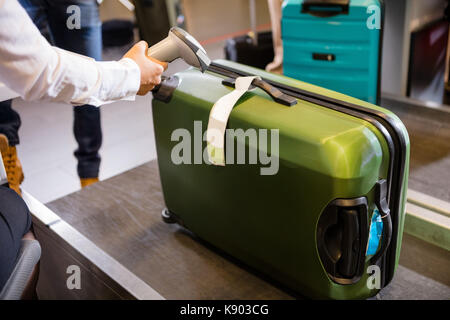 Donna tag di scansione sul bagaglio al check-in Foto Stock