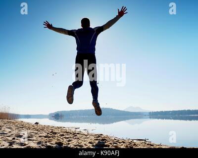 Uomo pazzo salto sulla spiaggia. sportsman battenti sulla spiaggia durante l'incredibile sunrise oltre l'orizzonte Foto Stock