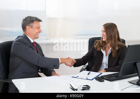 Due happy businessman stringono le mani con ogni altro in ufficio Foto Stock