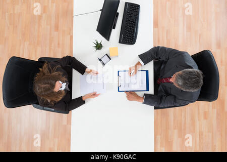 Angolo di alta vista di imprenditore maturo intervistando il candidato di sesso femminile per il lavoro Foto Stock