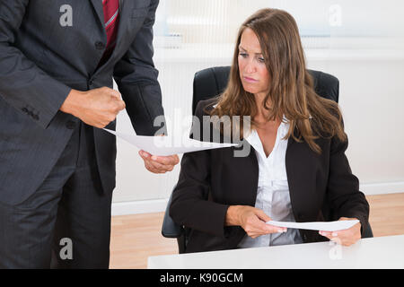 Close-up di imprenditore che mostra documento al dipendente di sesso femminile in office Foto Stock