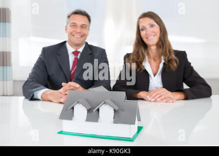 Due happy businessman guardando al modello di casa sulla scrivania Foto Stock