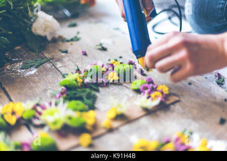 Fioraio effettuare decorazioni di fiori con lettere e colla. in interni luce naturale shot con piccole profondità di campo Foto Stock