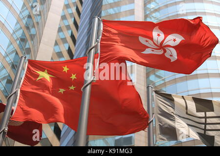 Cinese e Hong kong bandiere soffiare il vento con il palazzo di vetro sullo sfondo Foto Stock