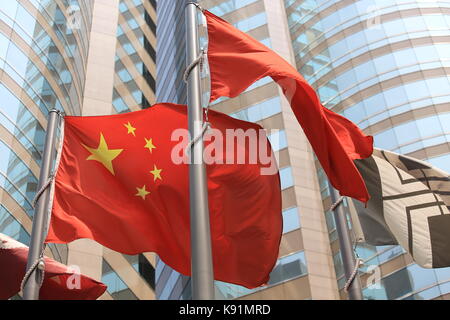 Cinese e Hong kong bandiere soffiare il vento con il palazzo di vetro sullo sfondo Foto Stock