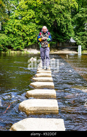 Uomo di attraversare il fiume e l'usura utilizzando pietre miliari a Stanhope, nella contea di Durham. Foto Stock