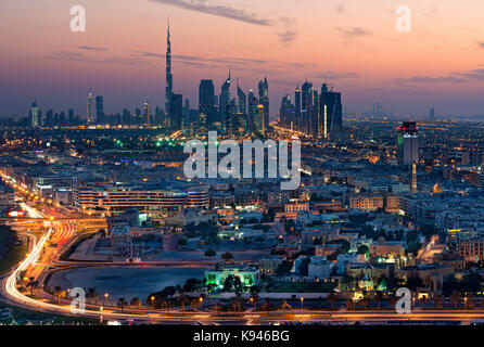 Paesaggio di dubai, Emirati arabi uniti al tramonto, con autostrada in primo piano e grattacieli in lontananza. Foto Stock