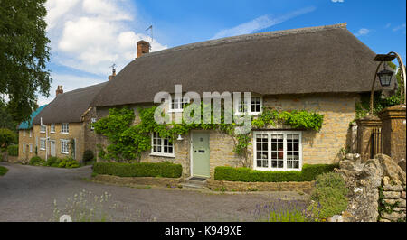 Cottage con il tetto di paglia in inglese il Cotswolds. Foto Stock